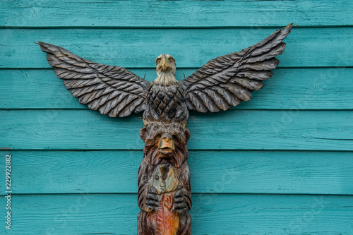 totem pole with bear and eagle in front of a turquoise background