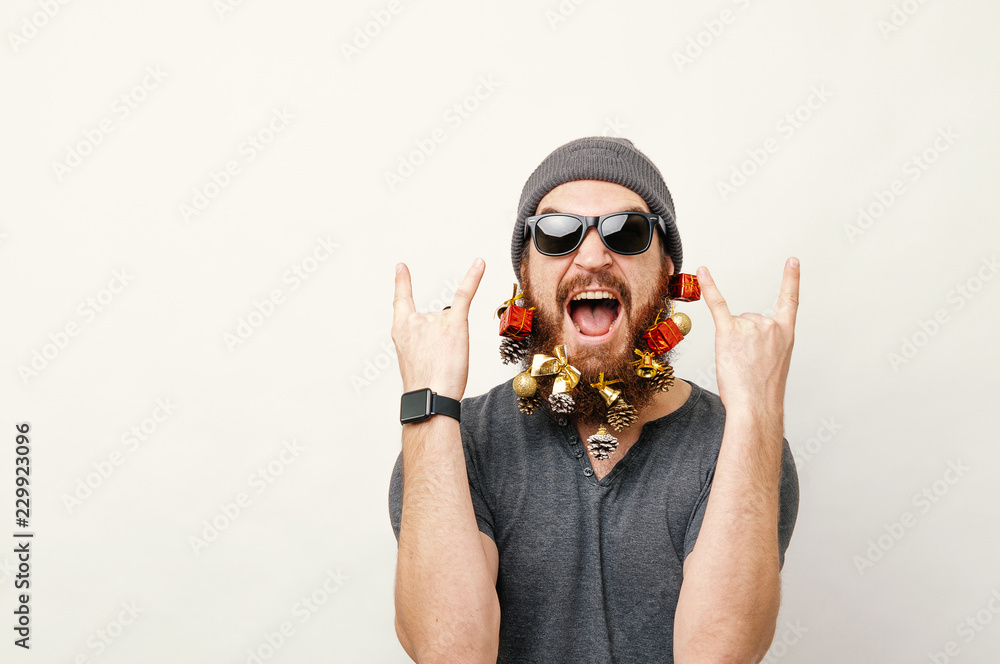 Portrait of cheerful man with christmas decorated beard showing rock sign - obrazy, fototapety, plakaty 