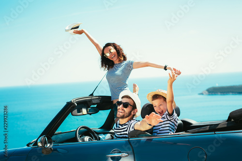 Happy family travel by car to the sea. People having fun in cabriolet. Summer vacation concept