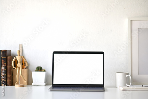 Workspace with blank white screen laptop on loft desk.
