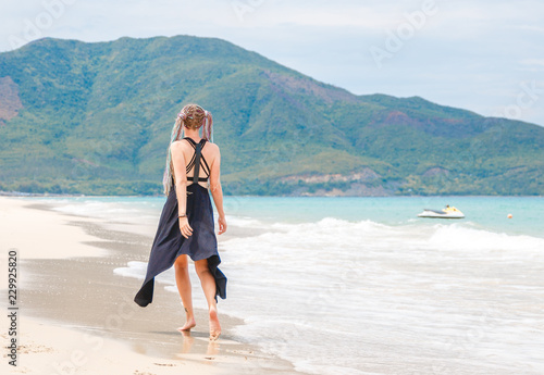 beautiful girl in a black dress walks on the beach