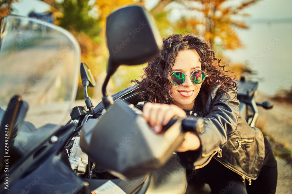 Young woman resting sitting on a motorcycle . Travel and tourism concept Young woman resting sitting on a motorcycle . Travel and tourism concept