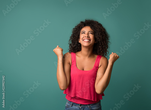 Happy woman celebrating her success on blue background © Prostock-studio