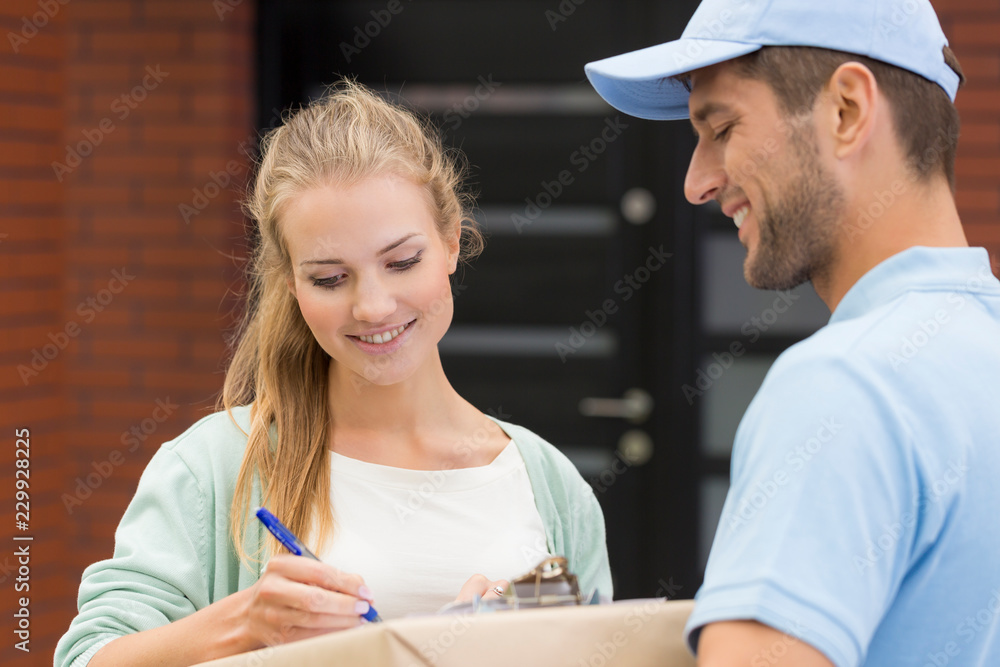Obraz premium Professional courier and smiling woman signing receipt on box