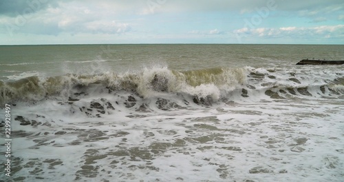 raging waves. Water from the river was mixed with sea water. Muddy water in the sea. Splashes from the waves bumping against the rocky shore