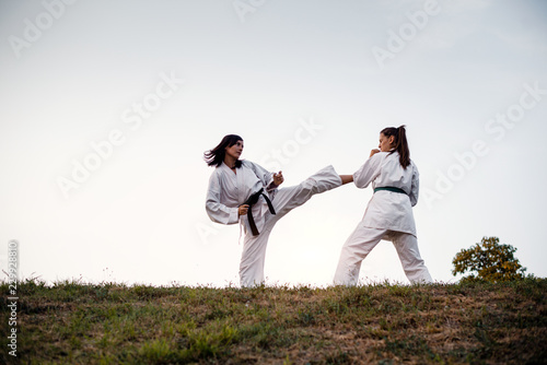 Martial artists training on top hill at sunset.