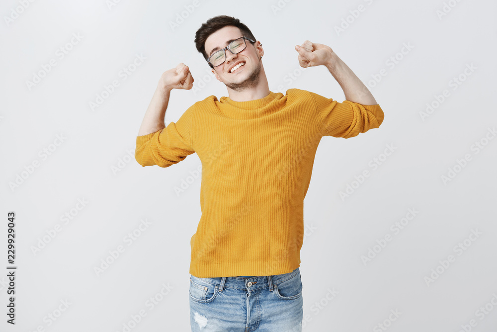 Guy finishing work stretching with hands raised sideways resting muscles as feeling tired, dreaming about nap or sleep standing over gray background in glasses and yellow sweater exhausted Guy finishing work stretching with hands raised sideways resting muscles as feeling tired, dreaming about nap or sleep standing over gray background in glasses and yellow sweater exhausted