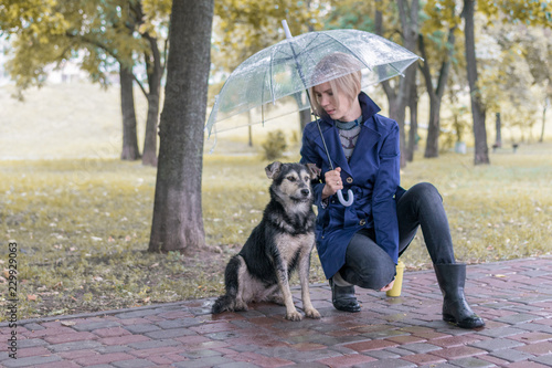 Woman under an umbrella with a dog in the park. Friendship of man and dog.