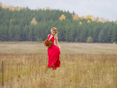 Wallpaper Mural A beautiful girl in a long red dress with a rowan bouquet in her hands is walking in a field on an autumn afternoon Torontodigital.ca