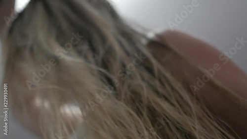 The girl the blonde dries hair a hair dryer. Hot air damage to hair
