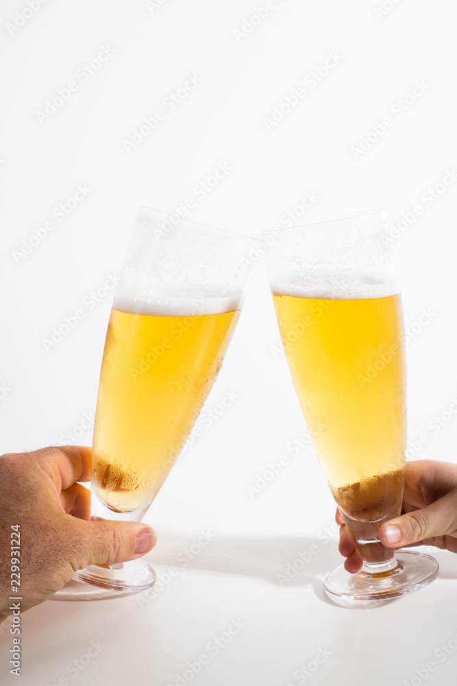 Two full glasses of beer set against a white background Two full glasses of beer set against a white background