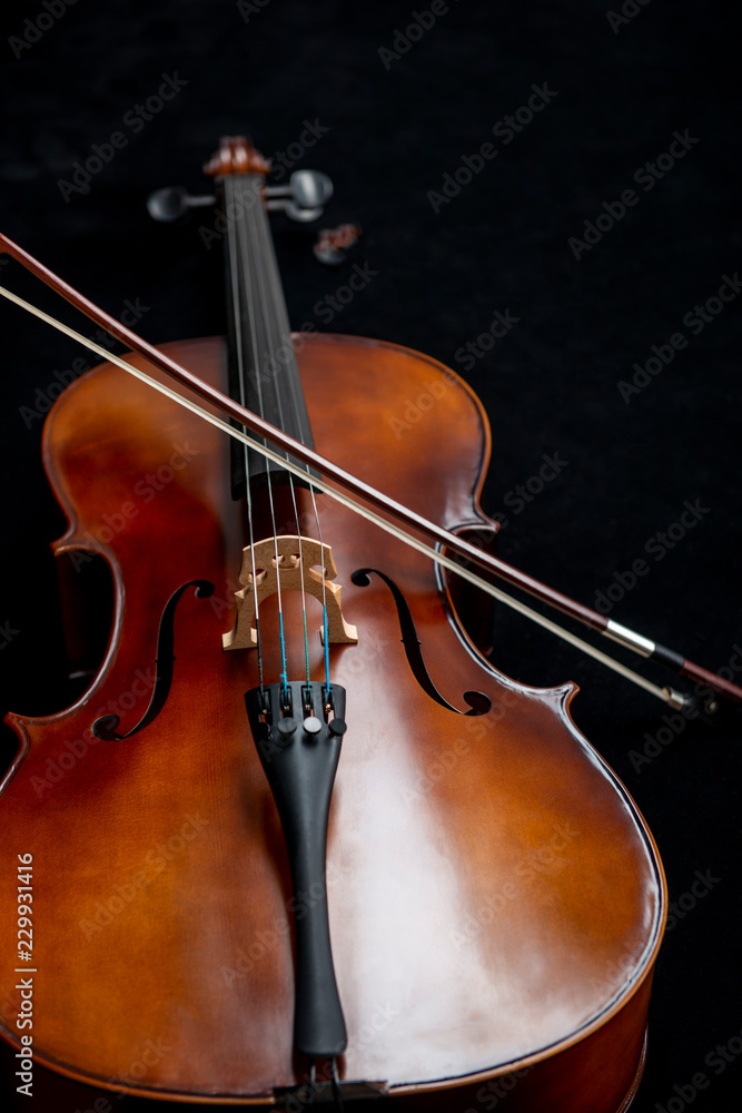 Close up of a cello and a bow set against a black background Close up of a cello and a bow set against a black background