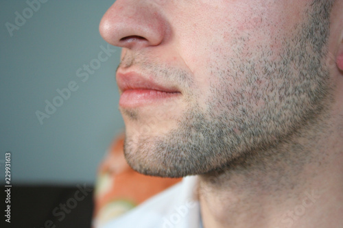 A man's face with a slight beard. A few days beard on the guy's chin. Macro picture taken from the profile. photo