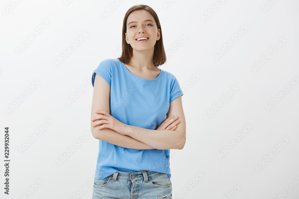 Self-assured attractive european girlfriend in blue blouse, raising nose and looking with satisfied smile at camera, holding hands crossed on chest, being confident and snobbish over grey wall Self-assured attractive european girlfriend in blue blouse, raising nose and looking with satisfied smile at camera, holding hands crossed on chest, being confident and snobbish over grey wall