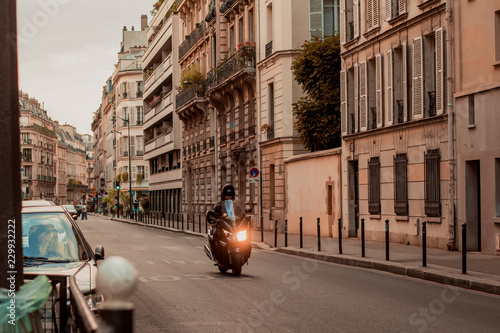 The guy on a motorcycle rides in the evening on the road on a street in Paris.