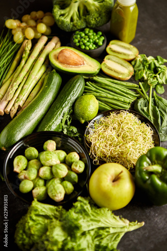 Green healthy food composition with avocado, broccoli, apple smoothie cucomber asparagus kiwi bean. Placed on dark background. Top view.