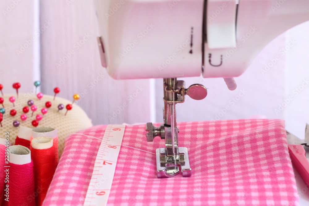 Electric sewing machine and accessory set isolated on pink background