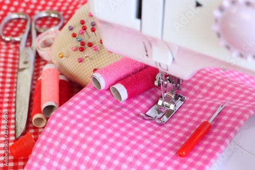 Electric sewing machine and accessory set isolated on pink background