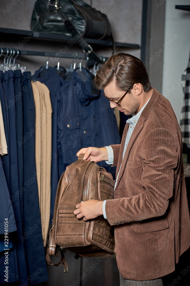 man in eyeglasses holding backpack while shopping in store man in eyeglasses holding backpack while shopping in store