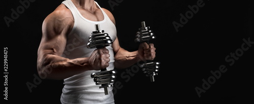 Strong athletic man with dumbbell showes muscular body