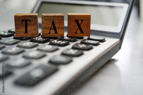 TAX on wooden blocks with blured calculator background