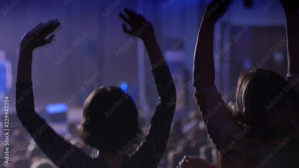 Cheerfully dancing jumping hands in air female fans at the concert