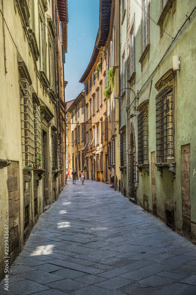 Tourists wandering in a small street in Lucca, Tuscany