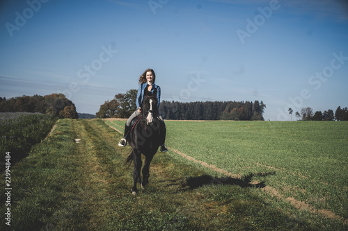 Junge schöne Frau und schwarzes Pferd Ausritt, reiten, Derssur, Reiterin © Christina