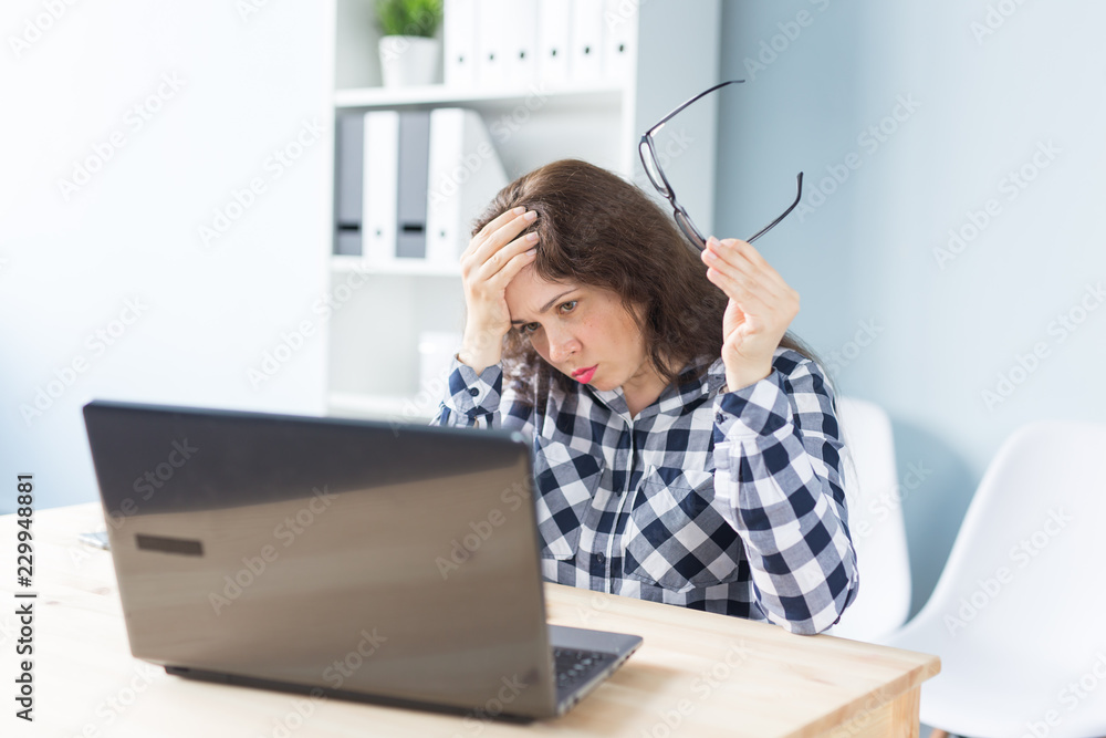 Working, business people and technology concept - young woman tired from working at the laptop and has a headache Working, business people and technology concept - young woman tired from working at the laptop and has a headache