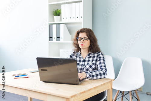 Technology, business and people concept - Serious woman in glasses working at the computer in office