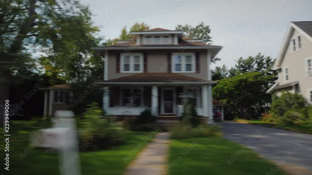 Ride along typical American suburbs. View from the window of the car - visible white wooden houses and beautiful lawns Ride along typical American suburbs. View from the window of the car - visible white wooden houses and beautiful lawns