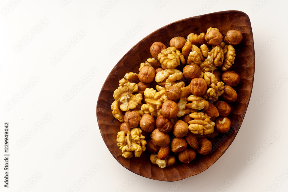 Overhead image of assorted nuts on wooden tray on white background with copy space Overhead image of assorted nuts on wooden tray on white background with copy space
