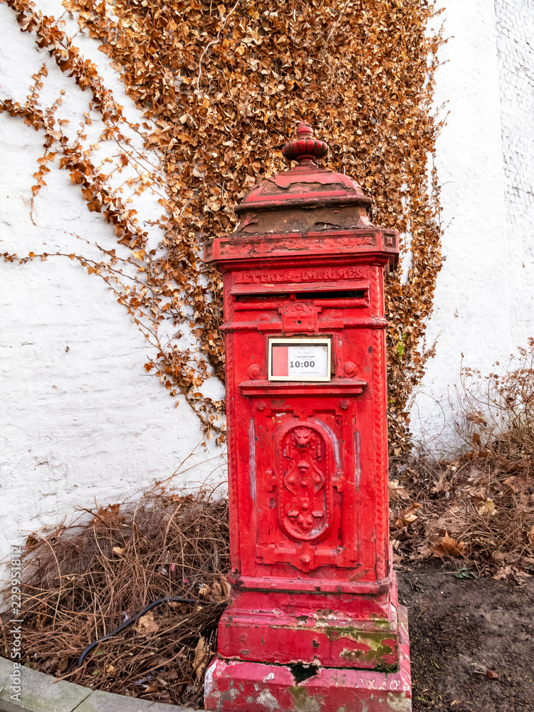 Old red postbox in the Belgian town of Verviers against a whitewashed building wall with a dried winter creeper plant Old red postbox in the Belgian town of Verviers against a whitewashed building wall with a dried winter creeper plant