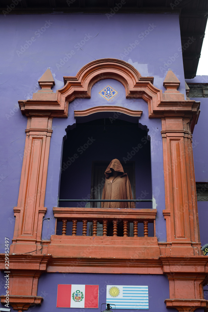 Lima purple building with window and hooded man sculpture. Perù