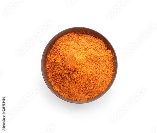 Bowl with red pepper powder on white background, top view