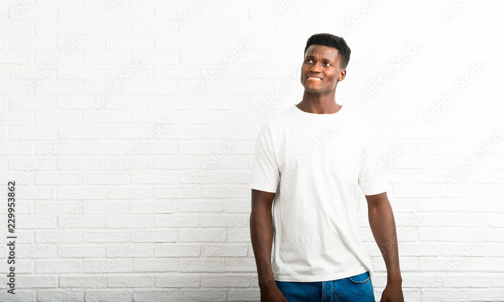 Dark skinned man having doubts and with confuse face expression while bites lip. Questioning an idea Dark skinned man having doubts and with confuse face expression while bites lip. Questioning an idea