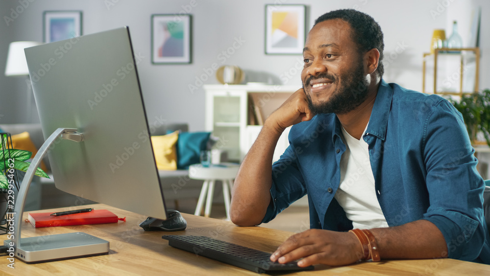 Portrait of the Happy Man Sitting at His Desk, Watching Videos at Home. In the Background Cozy Living Room. Portrait of the Happy Man Sitting at His Desk, Watching Videos at Home. In the Background Cozy Living Room.