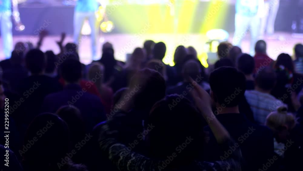 Crowd audience cheerfully applauds clapping hands at the concert performance