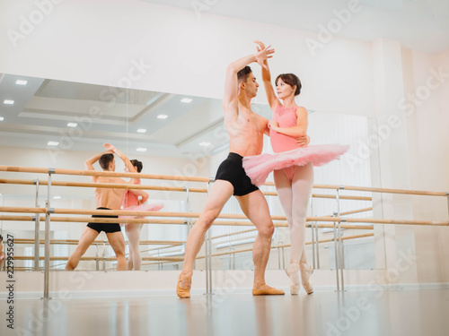 Rehearsal in the ballet hall or studio with minimalism interior. Young professional sensual dancer's couple in beautiful costumes dancing together