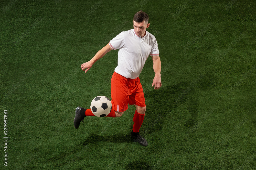 Football player tackling for ball over green grass background. Professional football soccer player in motion at studio. Fit jumping man in action, jump, movement at game. Football player tackling for ball over green grass background. Professional football soccer player in motion at studio. Fit jumping man in action, jump, movement at game.