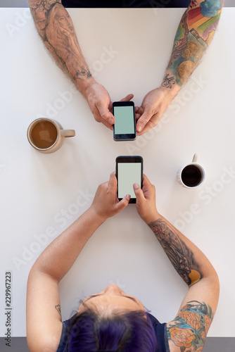 Couple looking at their own phones in cafe photo