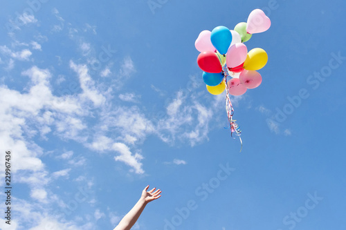 Hand letting balloons fly up in the sky photo