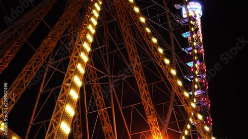 Colorful illumination bokeh effect light flashing on big ferris wheel roller coaster in amusement park fair at night sky