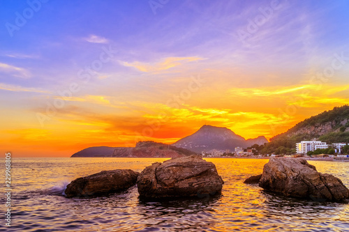 Gold colored sunset on the Adriatic sea coastline with Sutomore city in Montenegro, gorgeous seascape