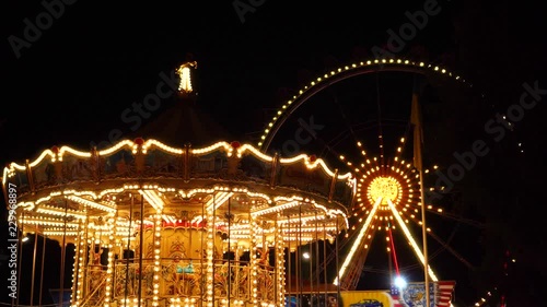 Flashing lights night illumination at amusement park carnival on vintage merry go round ferris wheel funfair attraction