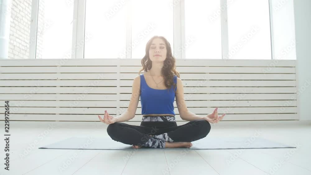 Yoga and home workouts concept. Young woman meditates while practicing yoga indoors Yoga and home workouts concept. Young woman meditates while practicing yoga indoors
