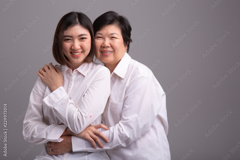Beautiful senior mom and her adult daughter are hugging, looking at camera and smiling Beautiful senior mom and her adult daughter are hugging, looking at camera and smiling