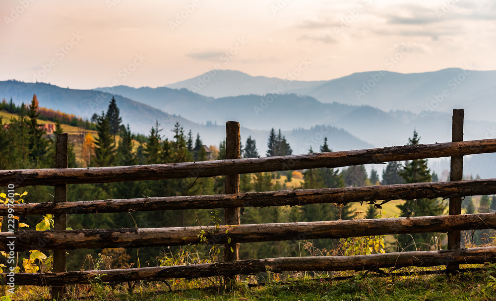 Wooden fence overlooking a mountain range and valley at sunset 