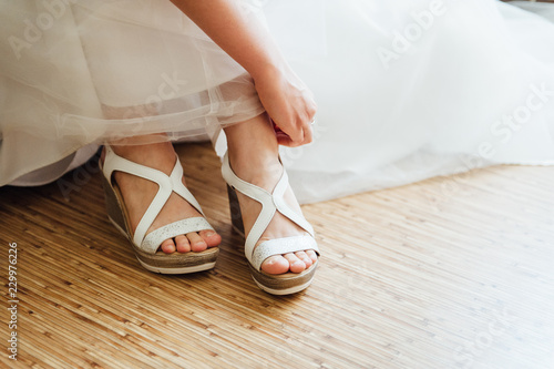 the bride puts on white shoes on feet