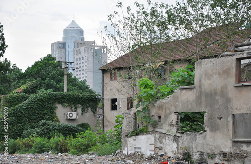 Old house on abridgment field in Shanghai with skyscraper behind